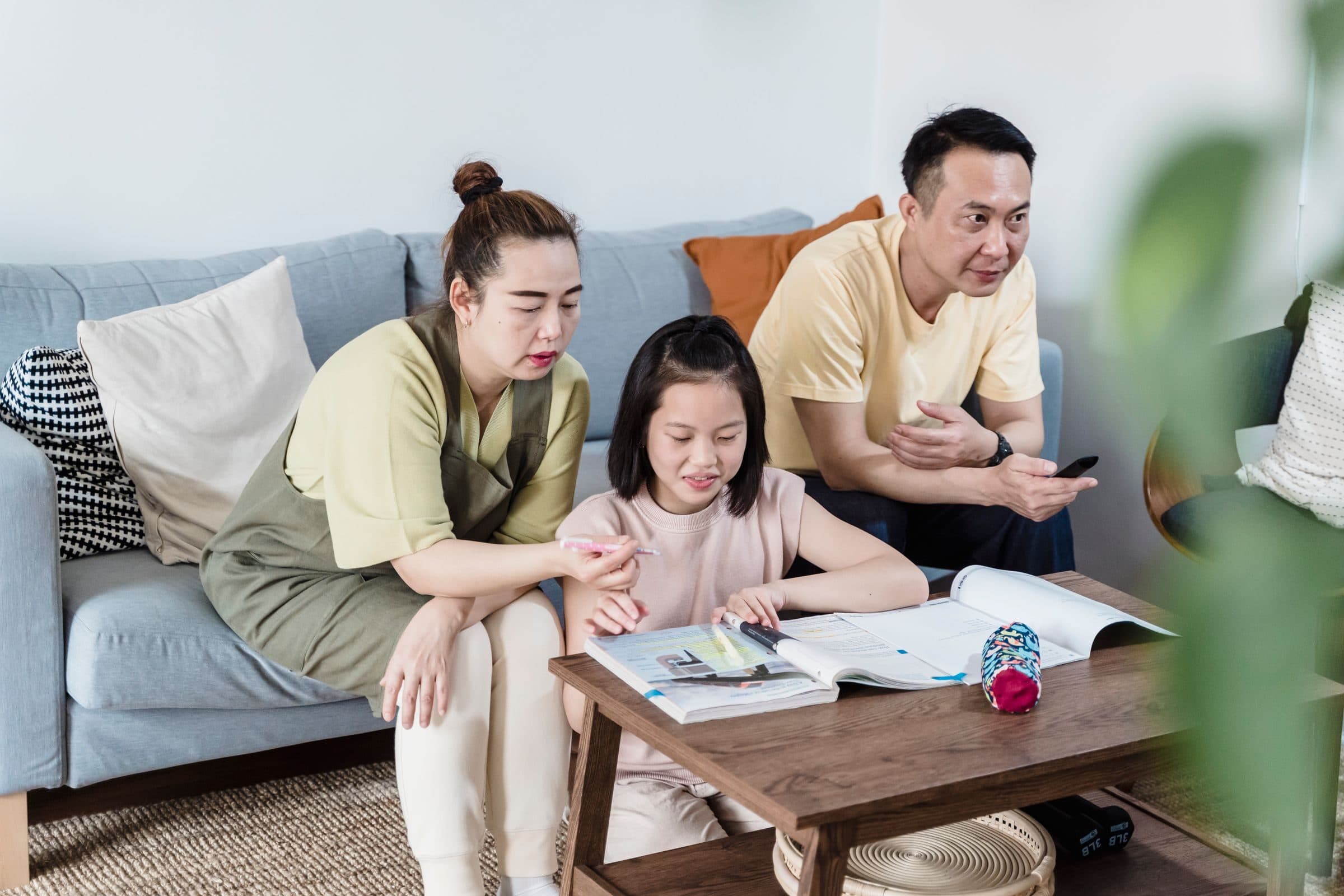 Parents helping their daughter with her homework at home